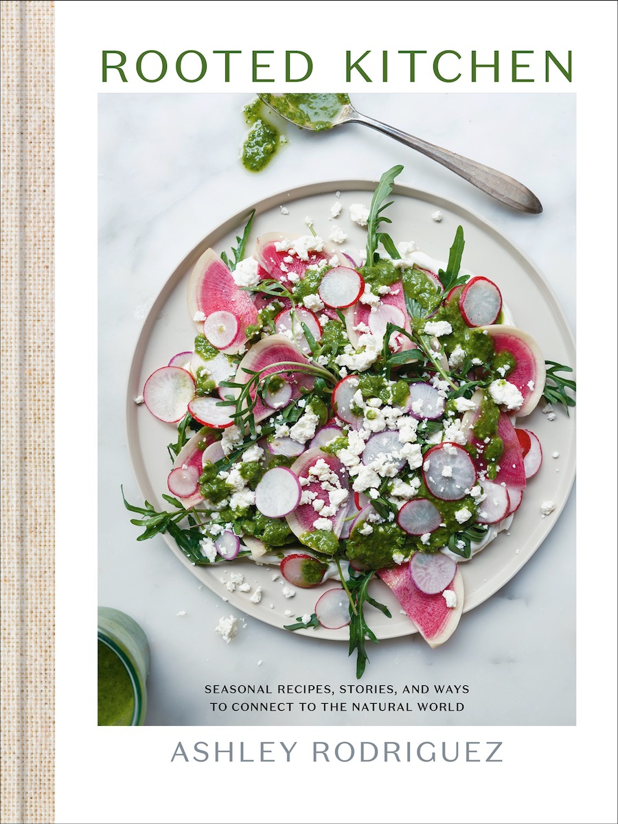 A salad on the cover of the cookbook Rooted Kitchen with radishes and sprinkled with cheese