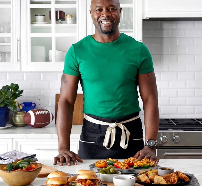 Eddie Jackson stands at a table of game day dishes in a white kitchen