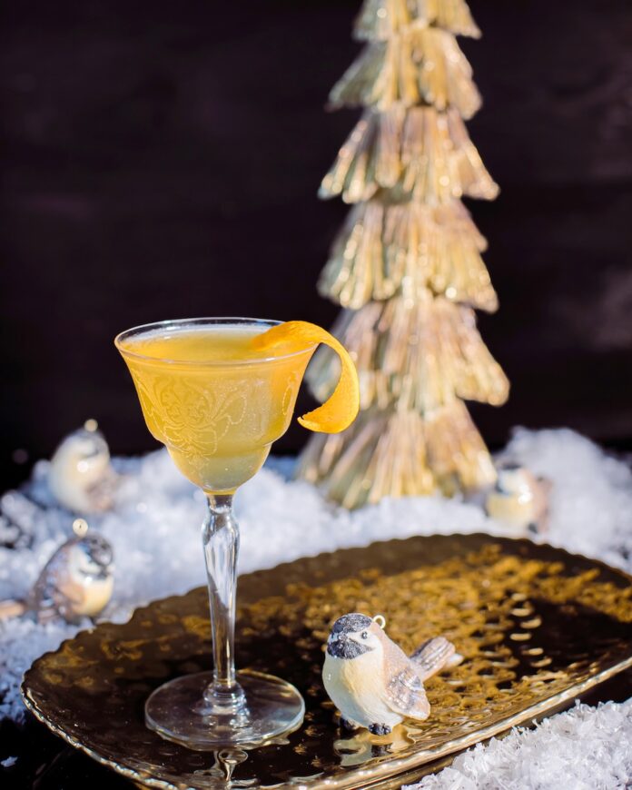 A nick and nora glass with a bright yellow Aviation cocktail in it