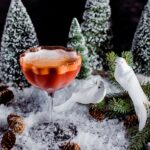 A Christmas cocktail with tequila and mezcal staged with two fake birds representing the two turtle doves in the song "Twelve Days of Christmas"
