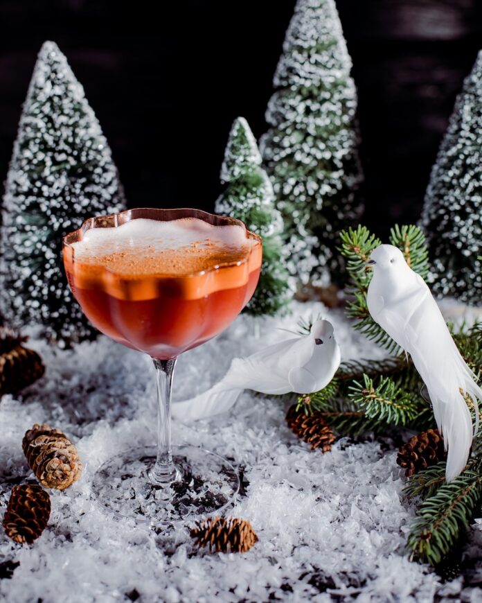 A Christmas cocktail with tequila and mezcal staged with two fake birds representing the two turtle doves in the song 