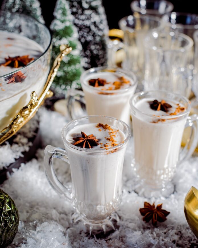 A set of festive coquito cocktail glasses staged on a holiday-themed table
