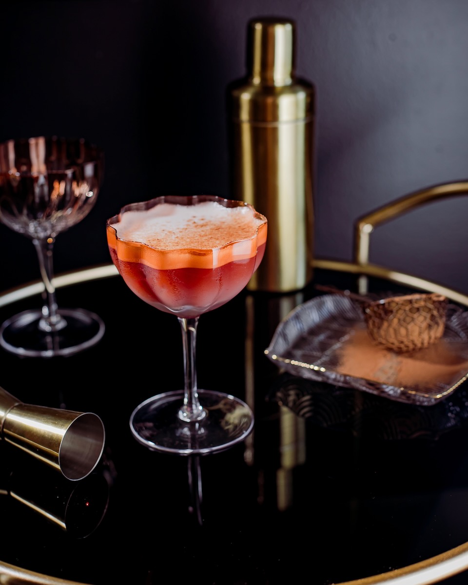A red-orange tequila and mezcal cocktail on a black background 