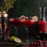 Three cranberry margaritas garnished with lime and staged for a Christmas table