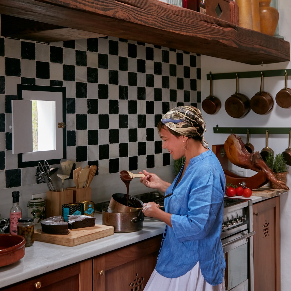 Maribel Lieberman at work in a kitchen with black and white checkered walls and pots and pans