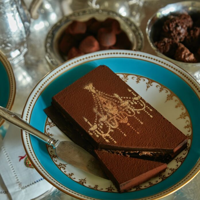 A slice of dark chocolate ganache with a lavish golden garnish on it