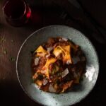 A plate of lamb tortellini with red sauce in a pale grey bowl
