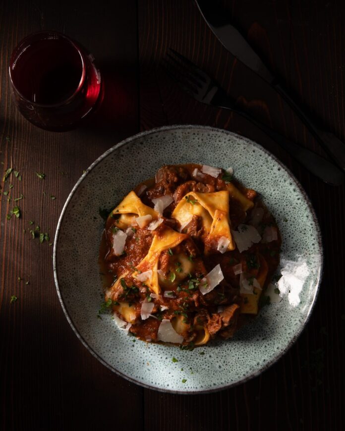 A plate of lamb tortellini with red sauce in a pale grey bowl