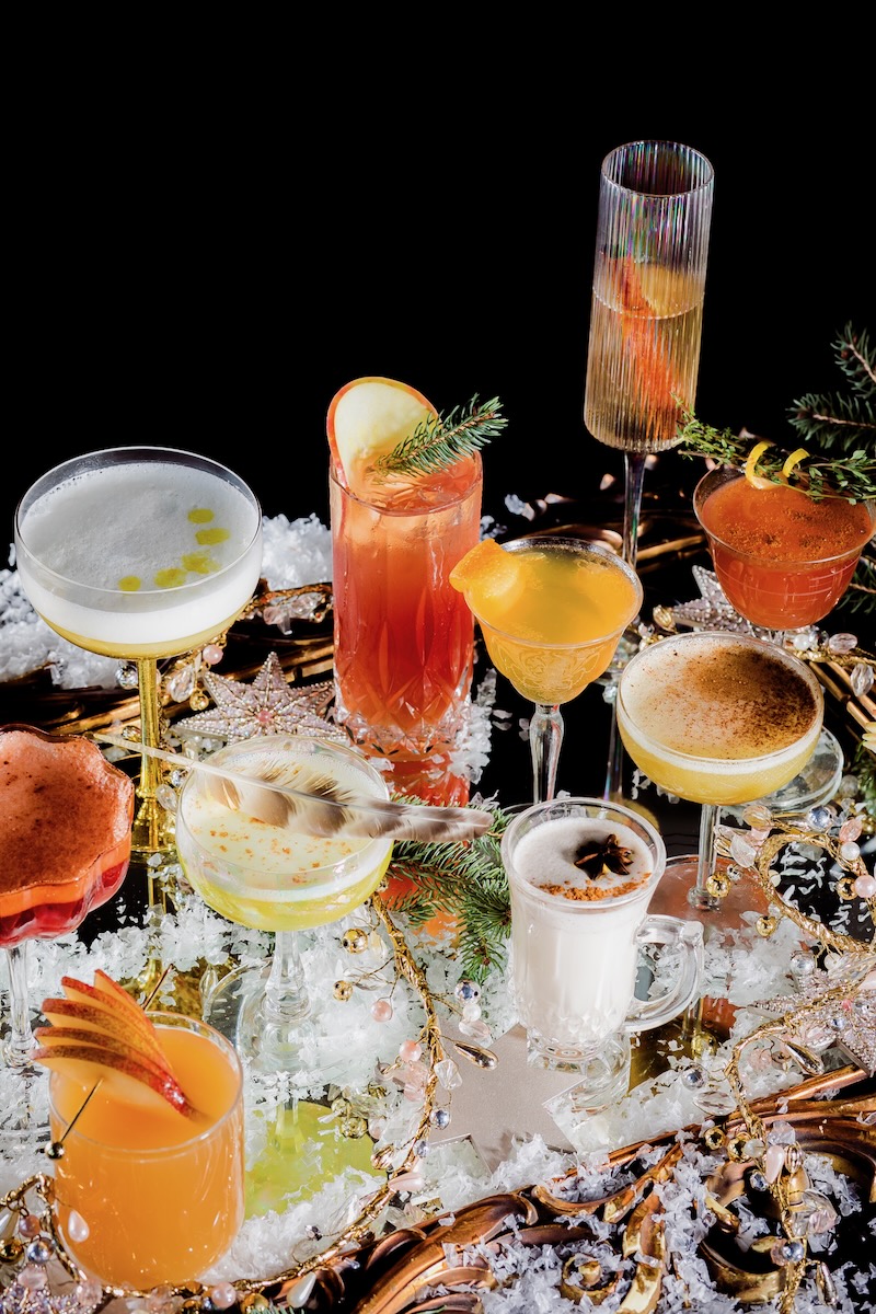 Twelve cocktails for Twelve Days of Christmas shot in a side view on a cheery, holiday decor table 