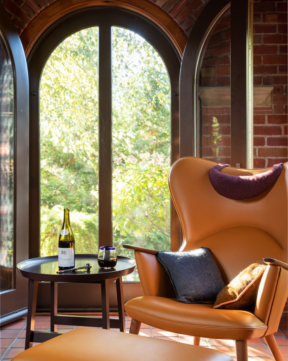 A cozy and inviting sitting area with a large arched window overlooking a lush, green garden.