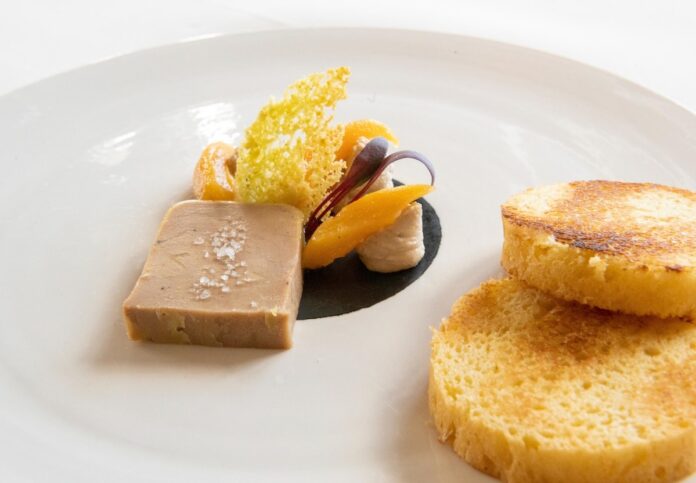 A vegan alternative to foie gras sits on a white plate on a white background
