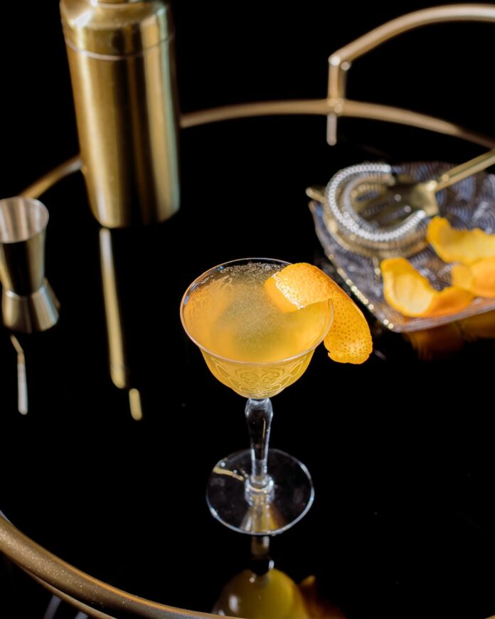 A mixture of a Paper Plane cocktail and an Aviation cocktail staged on a black background