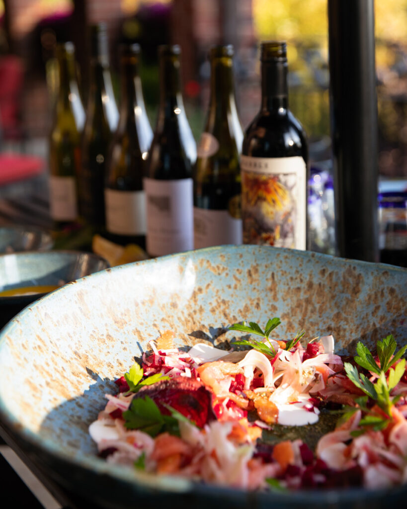 A colorful and fresh-looking salad featuring thin slices of cured salmon, diced beets, shaved fennel, and orange segments, artfully arranged on a plate and drizzled with a creamy crème fraîche dressing and lavender honey.