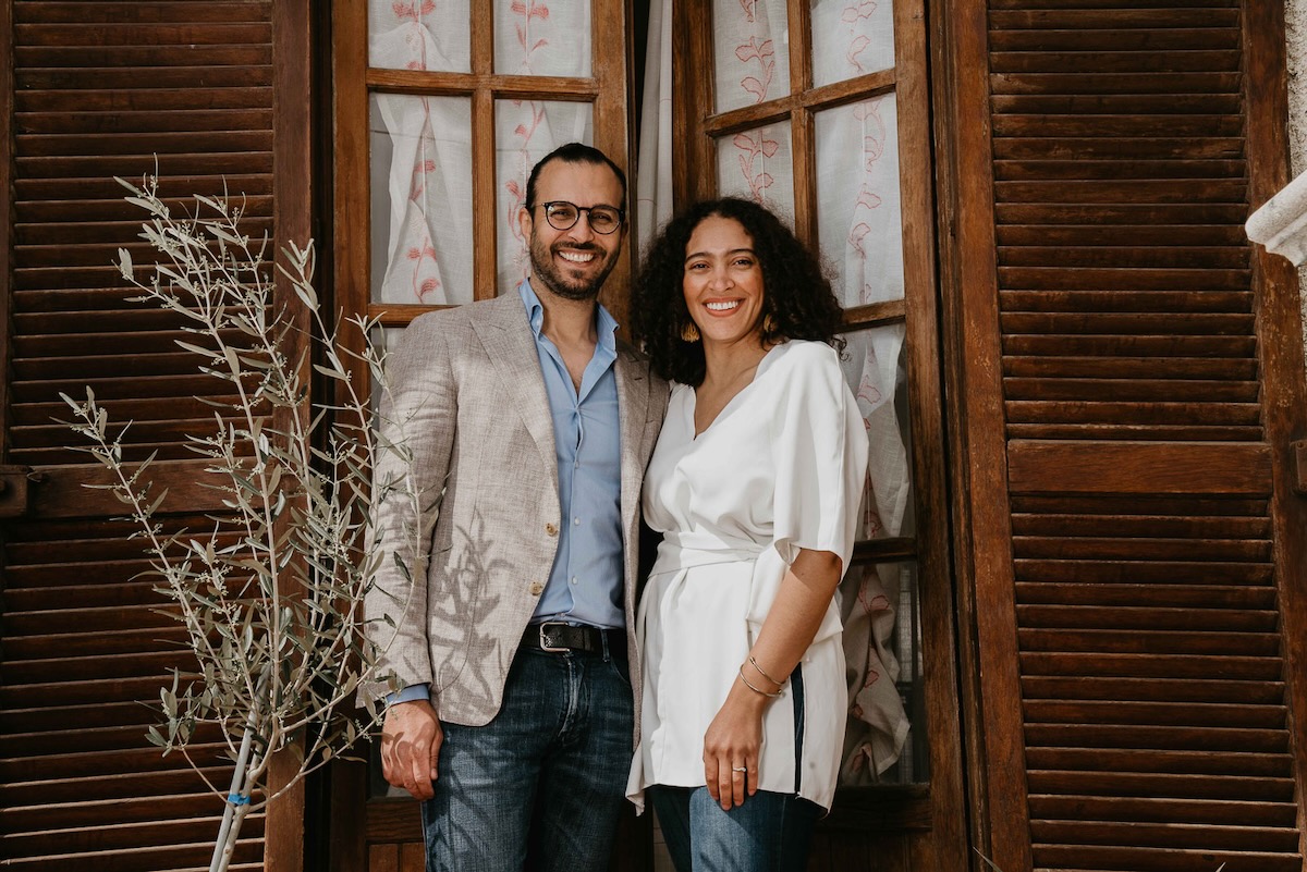Skylar Mapes and Giuseppe Morisani stand in front of a pair of French doors.