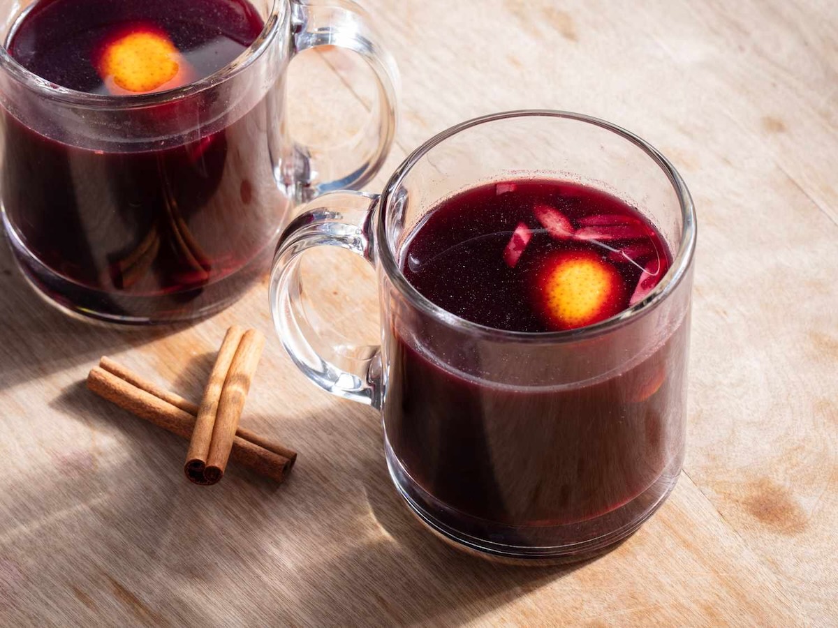 A glass of Glögg with sticks of cinnamon.