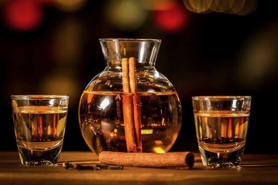 Greek Rakomelo in a pitcher with cinnamon sticks.