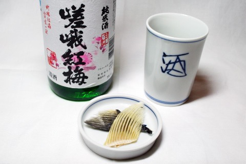 A hot cup of sake with the fin of the deadly fugu fish beside it.