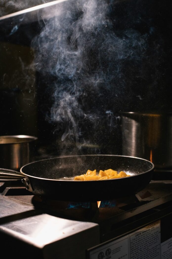 A sizzling pot at a restaurant on a black background.