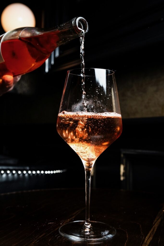A romantic glass of sparkling rosé wine on a black background