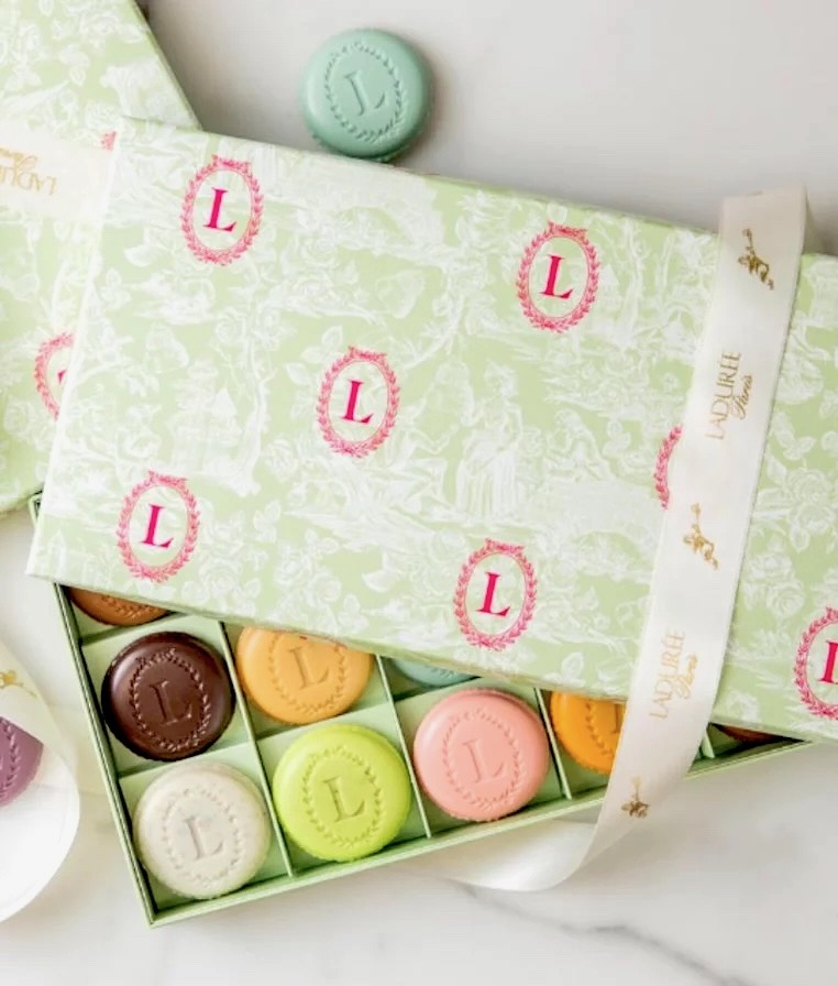 A box of chocolates wrapped in a green and pink cozy.