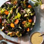 A plate of salad on a white background, paired with vinaigrette.