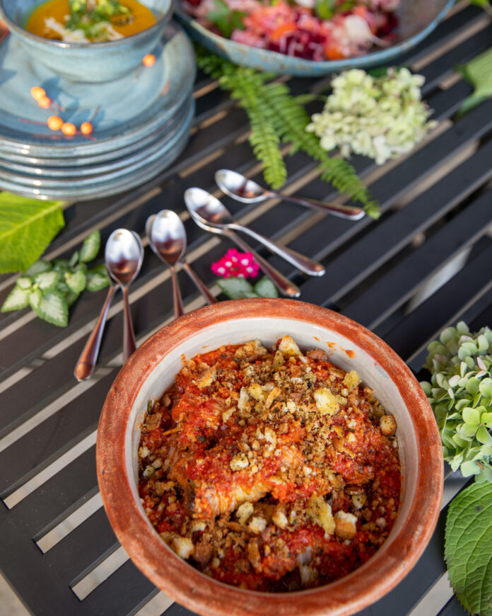 Vegan Chorizo Stuffed Napa Cabbage dish featuring napa cabbage leaves stuffed with a homemade vegan chorizo mixture, topped with a vibrant red harissa tomato sauce, and surrounded by fresh herbs and vegetables.