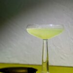 A light green cocktail in a martini glass, modeled after The Activator from The Substance.