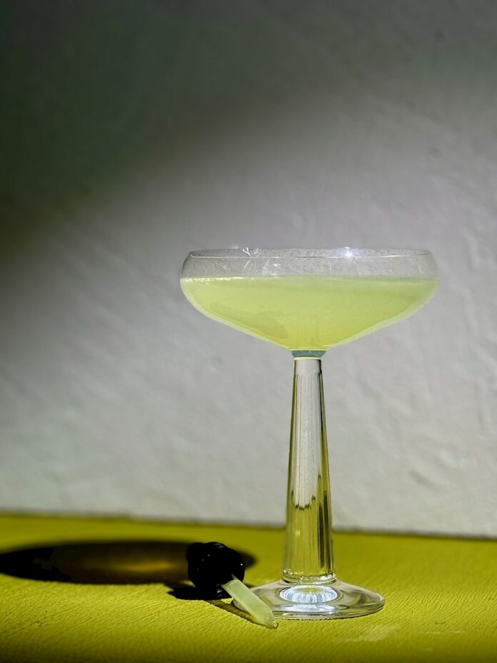 A light green cocktail in a martini glass, modeled after The Activator from The Substance.