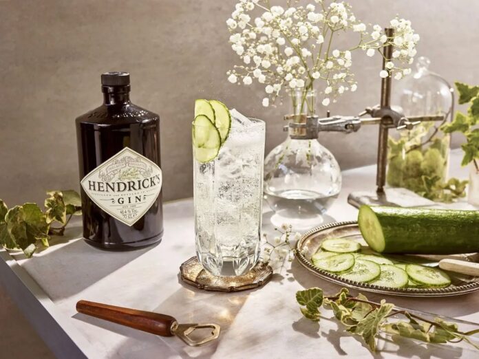 A bottle of Hendrick's gin staged beside cucumbe and baby's breath