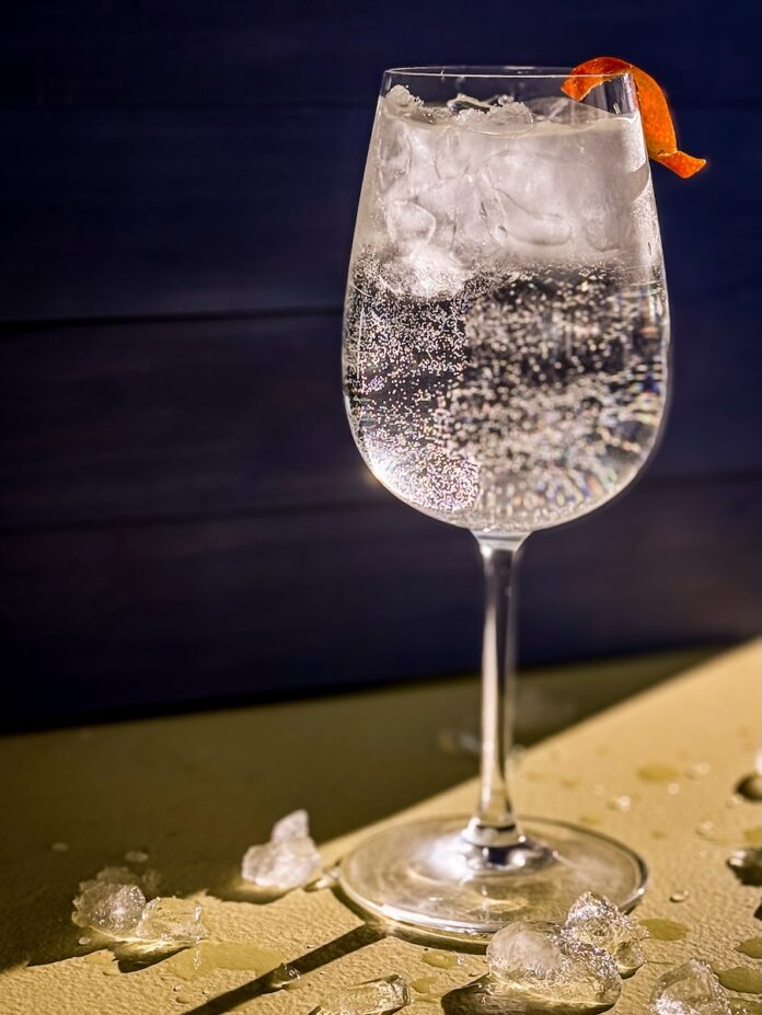 An adult spring break spritz, a clear cocktail in a wine glass.