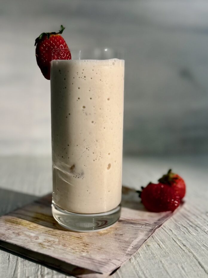 A tall smoothie glass holds a banana spiked smoothie