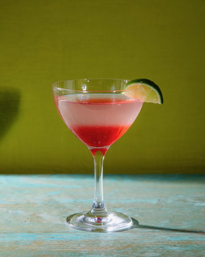 The Bend and Snap, a pale pink Legally Blonde cocktail on a green background.