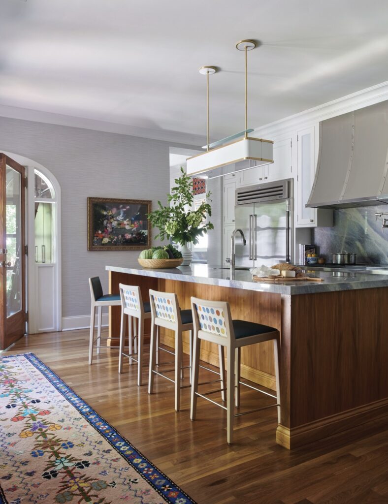 A Betsy Wentz designed kitchen with a marble and wood cabinet island in the center of the room.