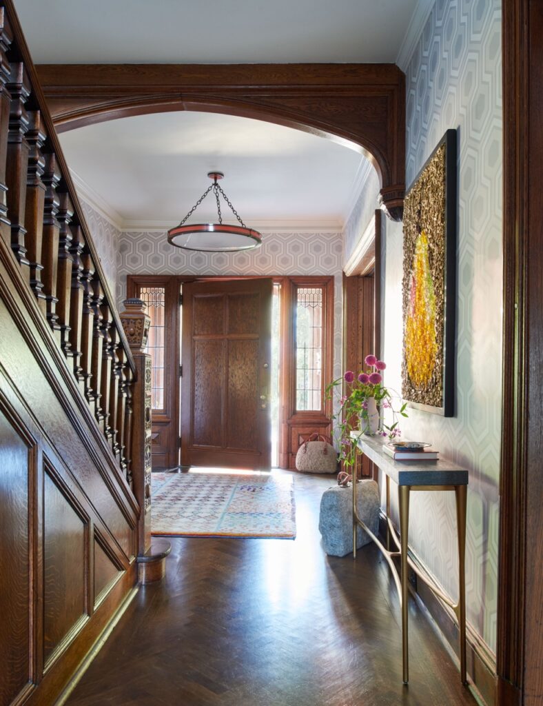 An entryway space with a brown staircase to the left and the same colored door straight ahead.