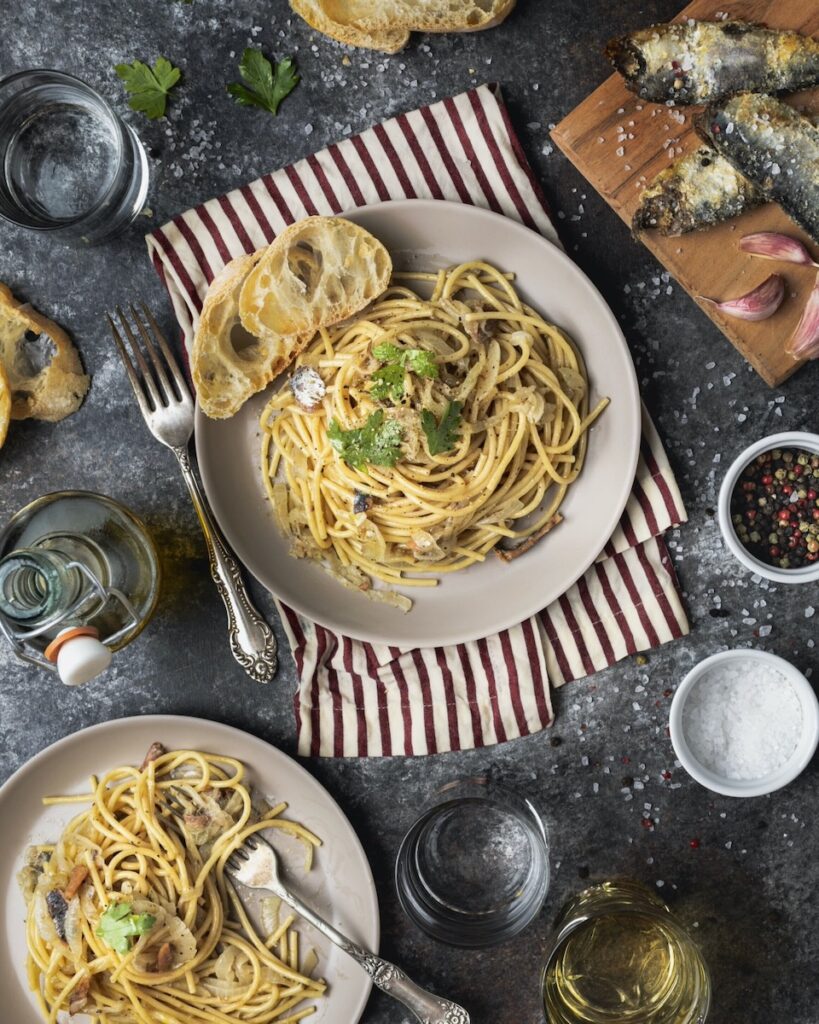 A plate of whole-wheat spaghetti (bigoli in salsa) on a striped placemat.
