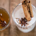 A glass of cremas with anise and a cinnamon stick in it.