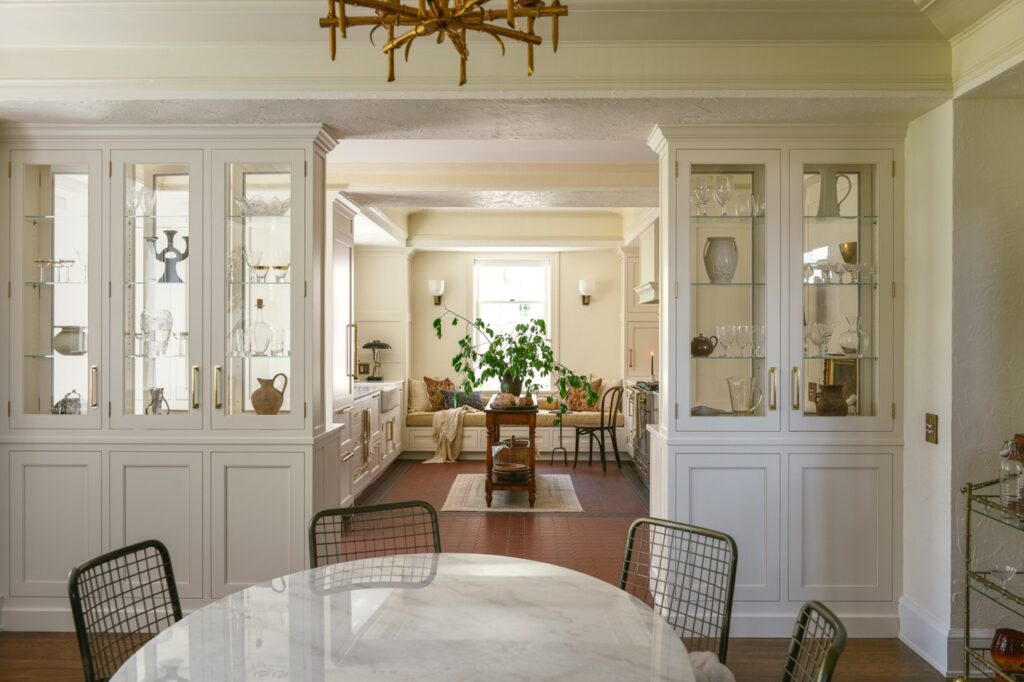 A dining area outside of the Cruze Architects new kitchen space which has a white dining table with black chairs and white walls.