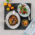 A bowl of soupe joumou on a tablecloth on a white background.