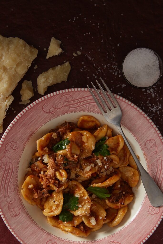 A plate of handmade orecchiette pasta with a meat sauce.