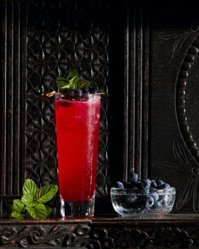 A glass of Market Alley Gin Punch on a black backgroound.