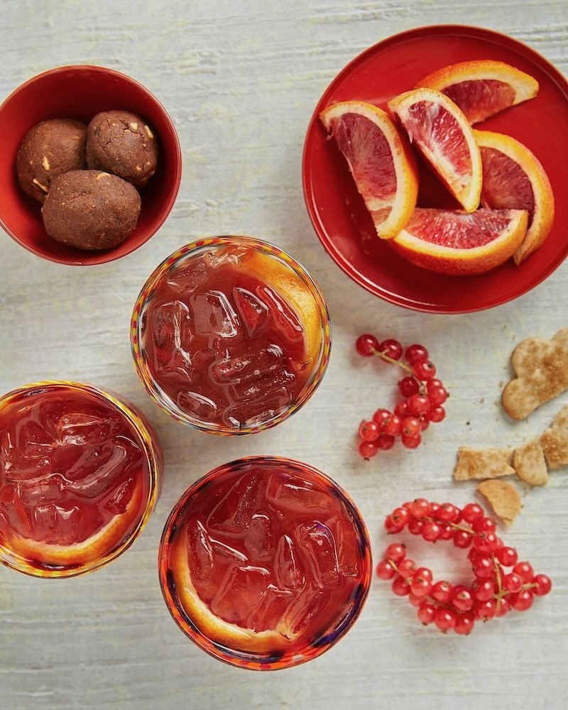 An apple cider negroni surrounded by orange peels and other delicious ingredients.