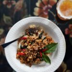 Pad Krapow Gai in a white bowl on a black background.