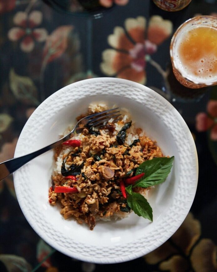 Pad Krapow Gai in a white bowl on a black background.