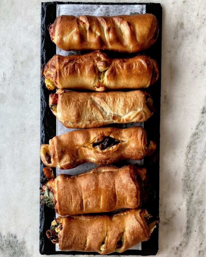 A set of pepperoni rolls on a black plate on a white background.