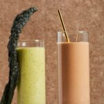 Pittsburgh Pirates smoothie, one brown with a gold straw sits beside a green smoothie both against a brown background.