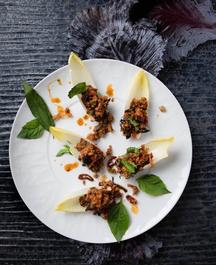 Lamb laab on a white plate on a black background.
