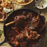Persian lamb stew for Nowruz, staged with other sides on a light brown table.