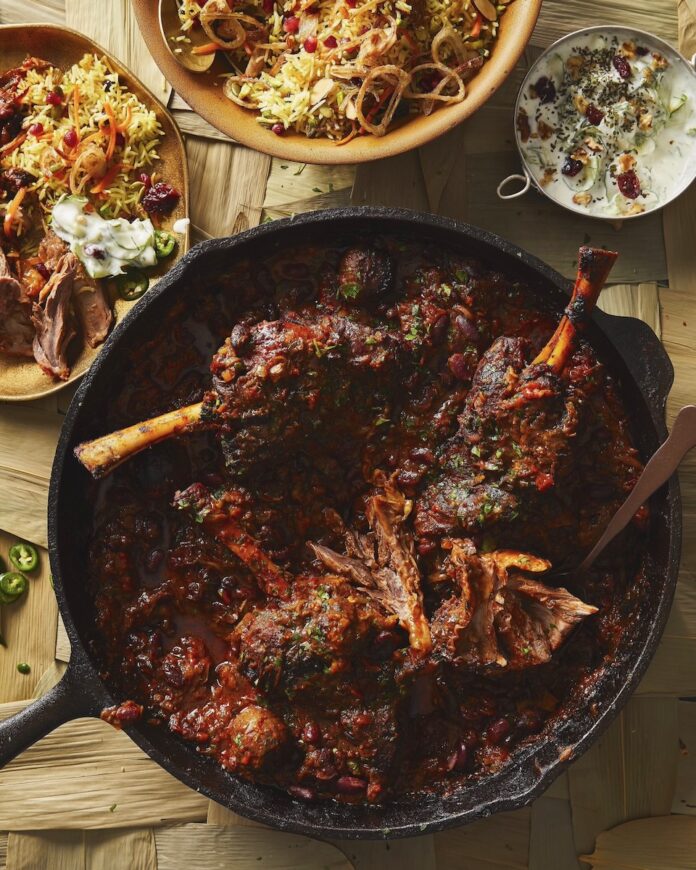 Persian lamb stew for Nowruz, staged with other sides on a light brown table.