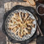 Sarde in Saor on a porcelain plate set on a rustic table.