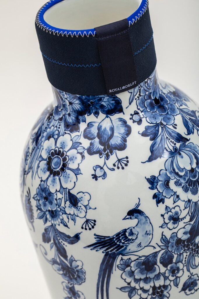 A blue and white delftware vase featuring a small bird design on it.